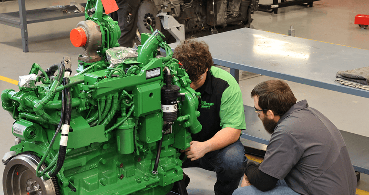 A student and instructor work on a diesel engine.