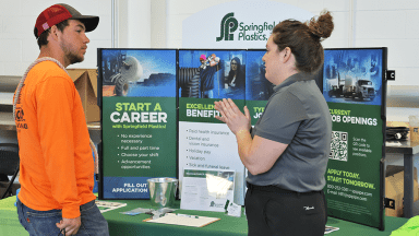 Employer at exhibit table talking to student