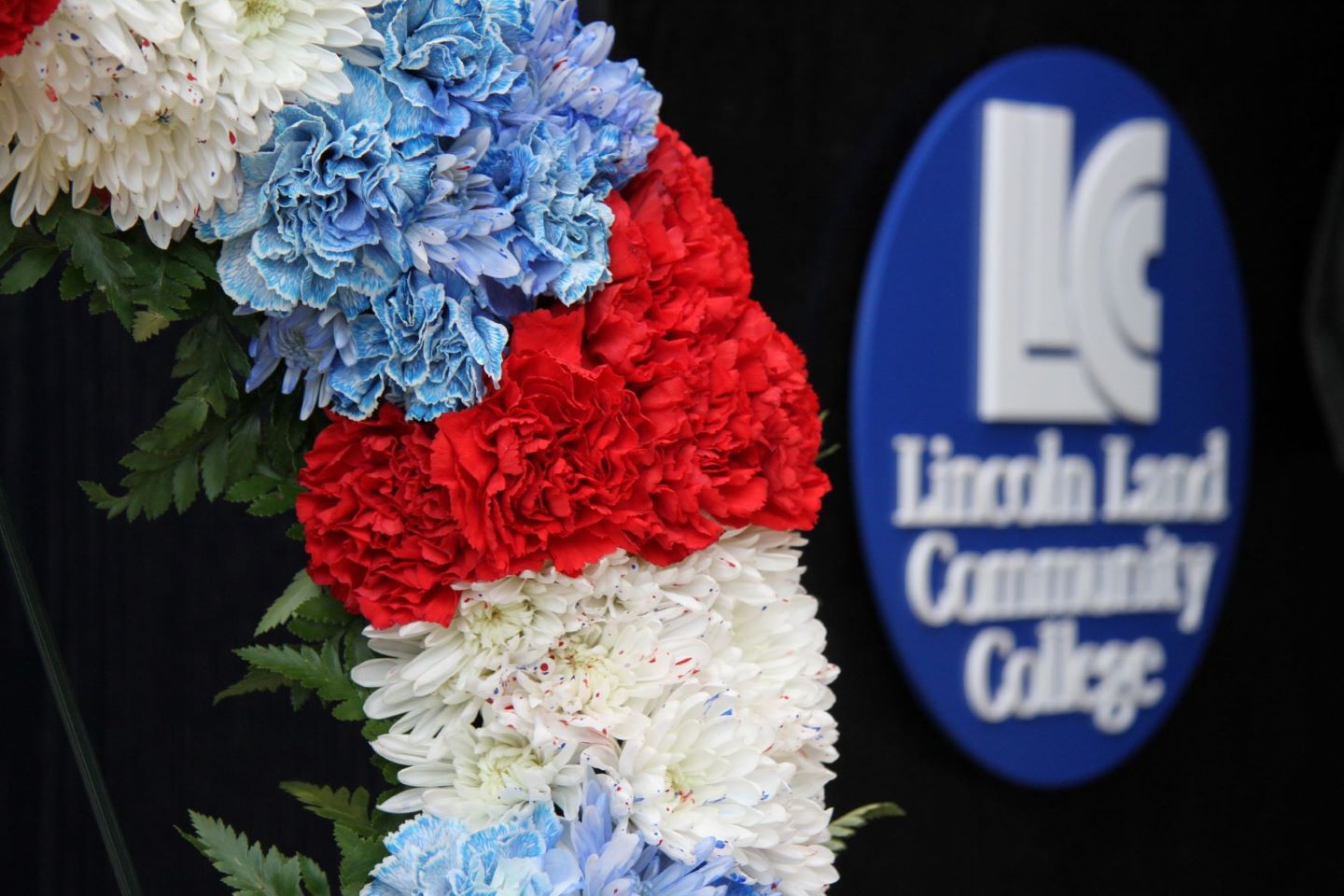 A wreath in front of the Lincoln Land Community College logo.