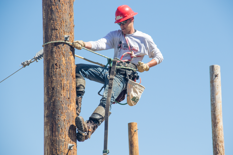An electrical distribution lineman student climbs a pole.
