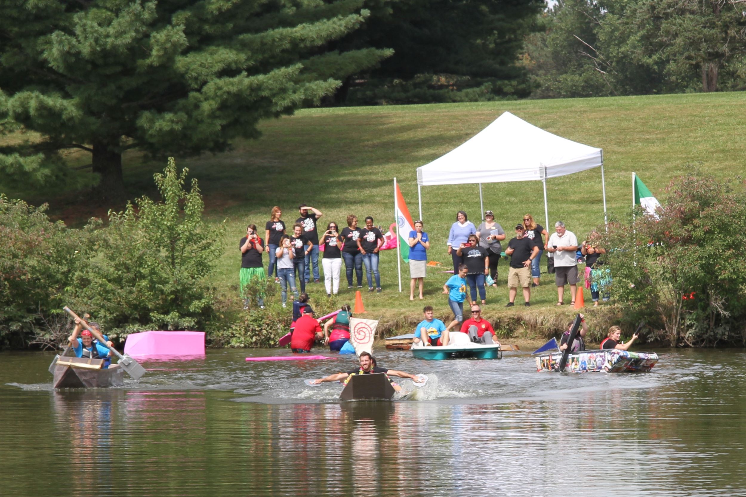 Teams in cardboard boats start paddling across the lake.