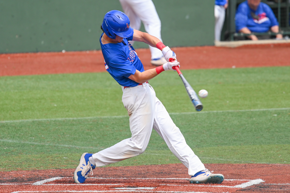 LLCC baseball player hits baseball with baseball bat