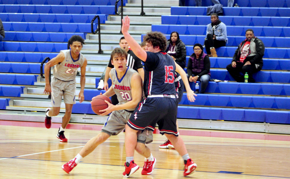 An LLCC men's basketball player dodges an opponent while holding onto the ball. 