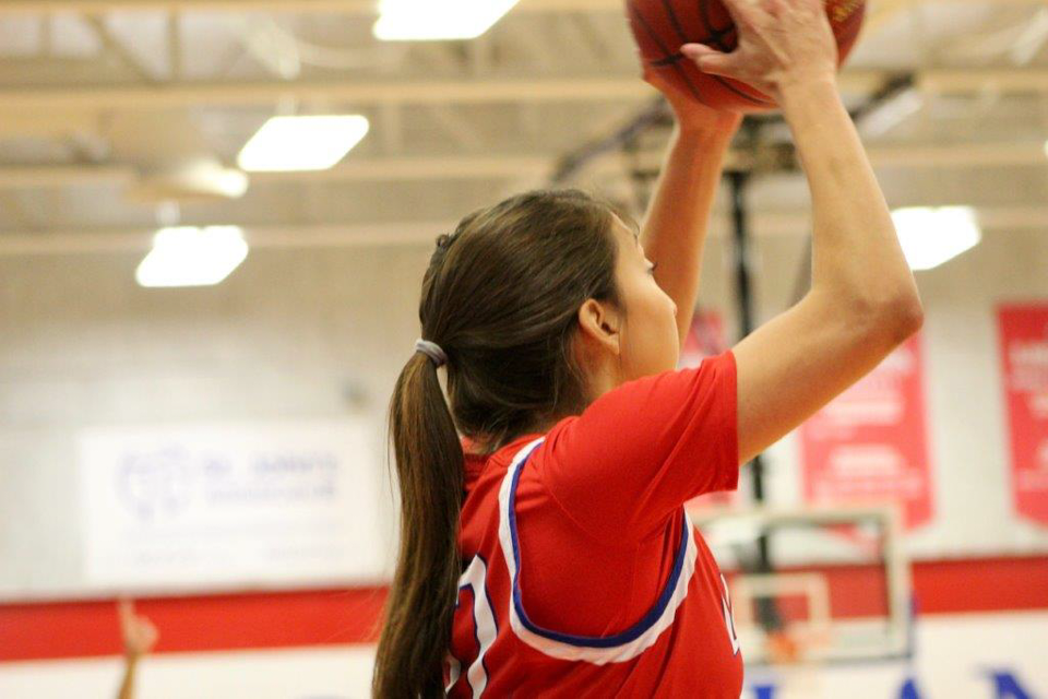 A women's basketball player prepares to shoot the ball. 