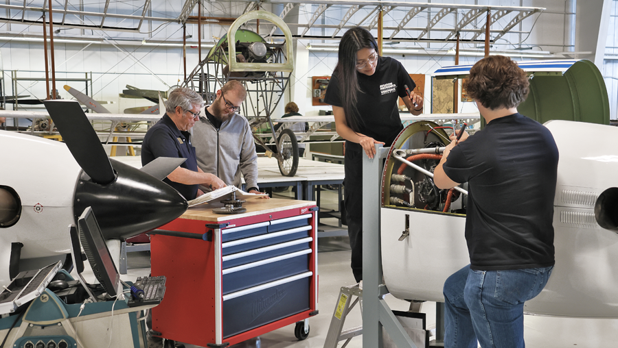 Aviation program director working with students on airplane engine in LLCC hangar
