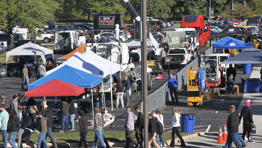 People walking through tents with exhibits and equipment 