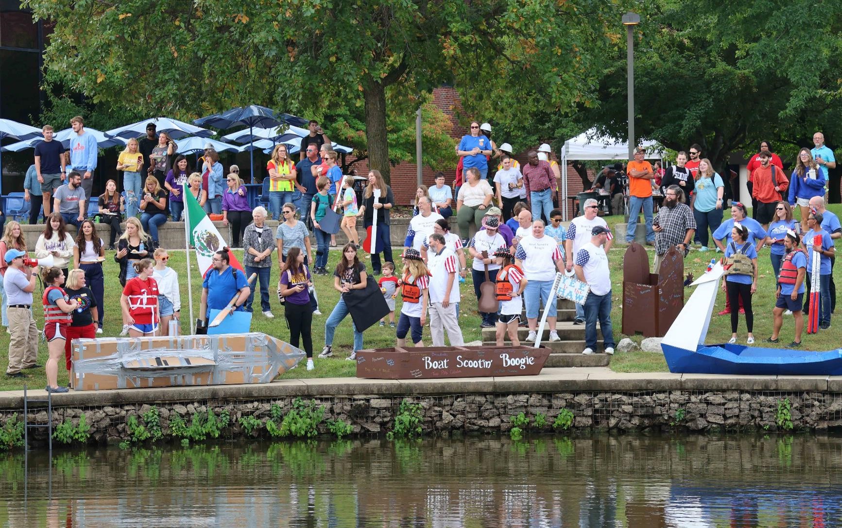 Boats getting ready to launch in regatta with members of the college community looking on.