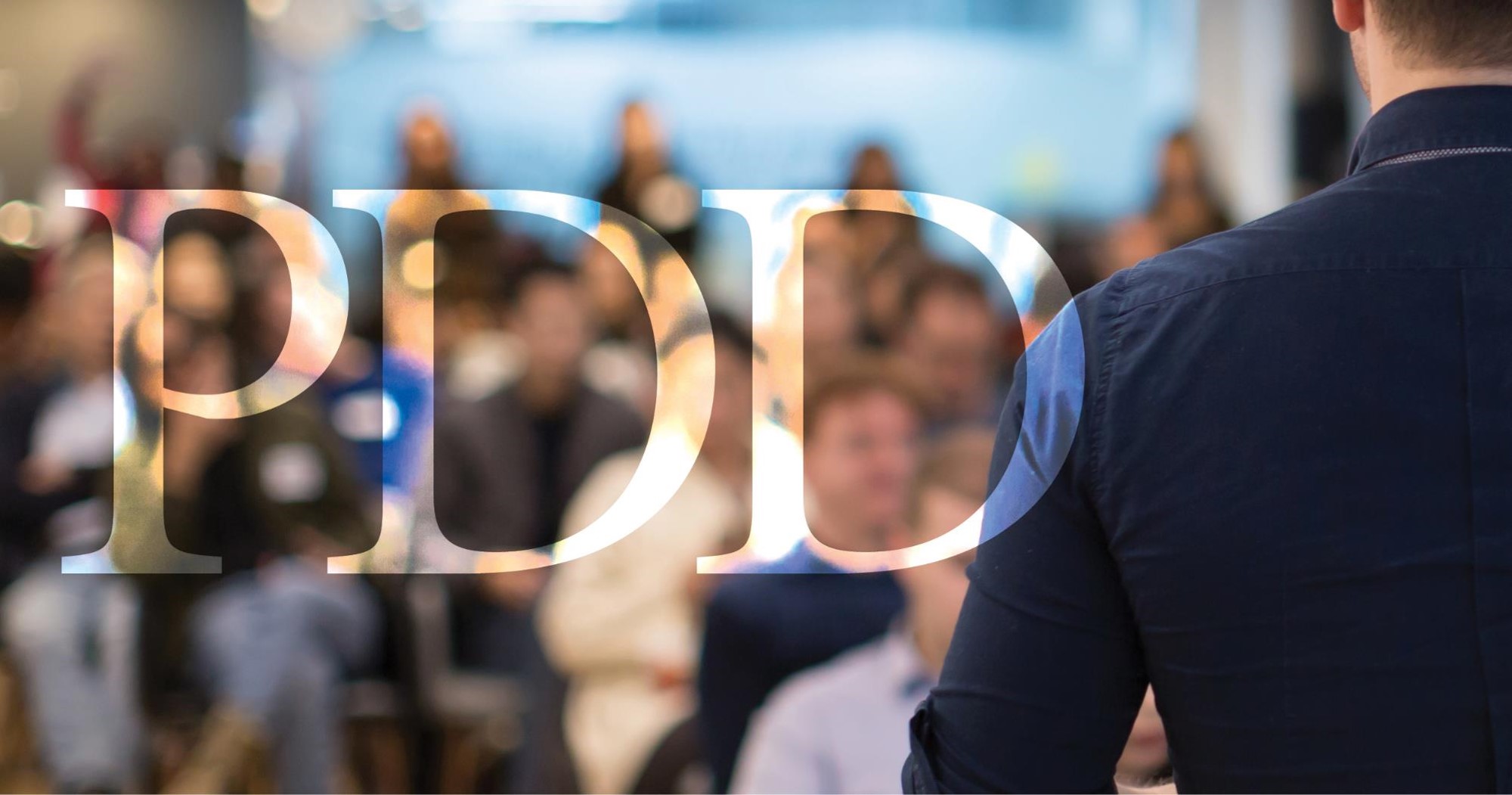 A man wearing a suit stands before a crowd.