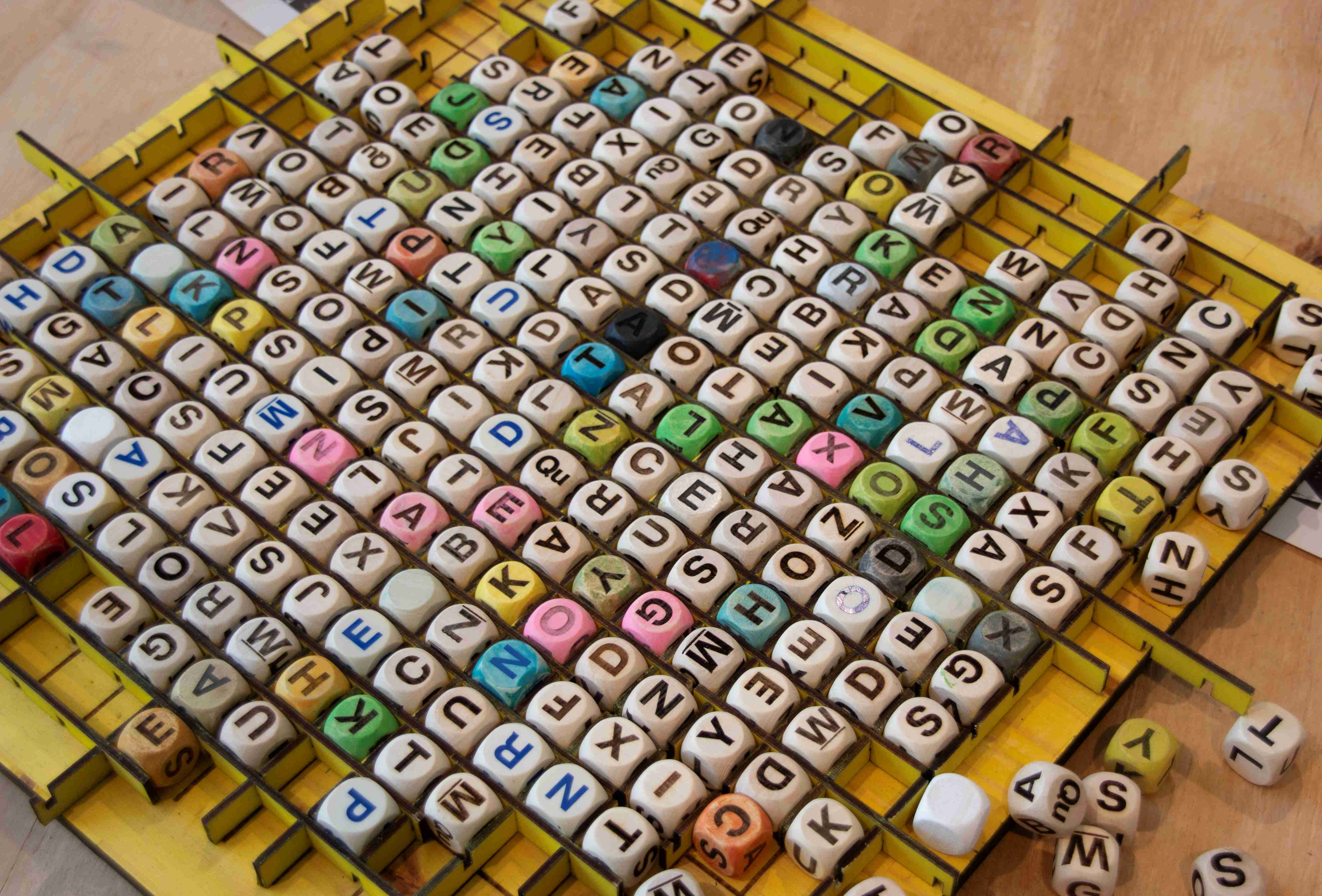 Many boggle letter dice on table