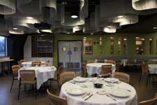 The inside of Bistro Verde: a dining room with round tables and place settings.