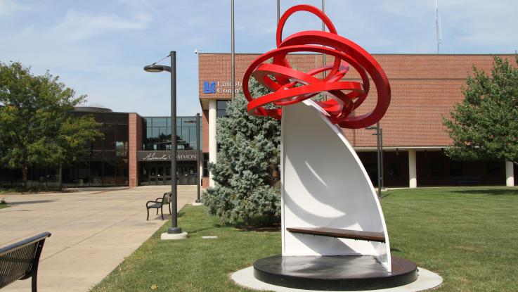Sculpture of 5 something in front of Menard hall.