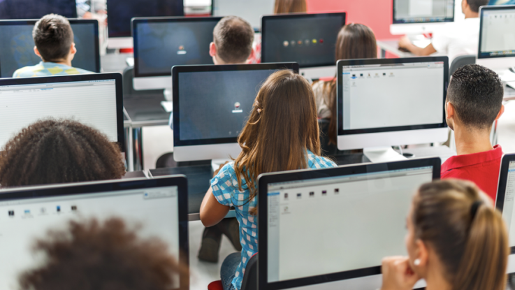 A classroom of students seated in front of Mac computers.