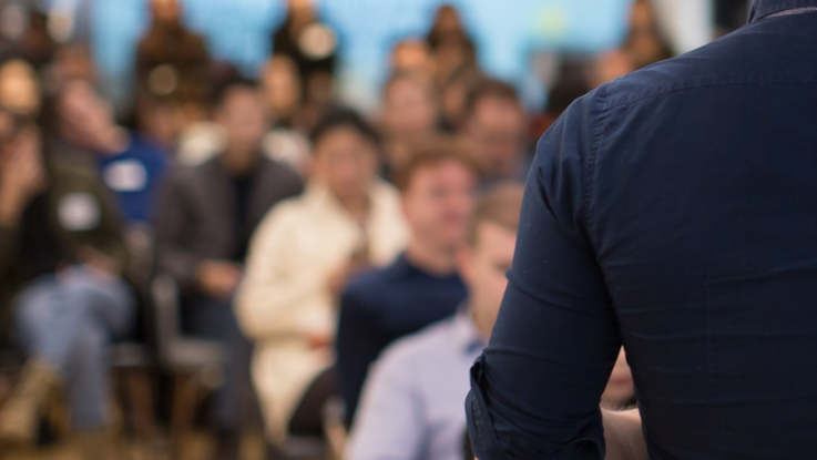 A speaker talks to a crowd of people