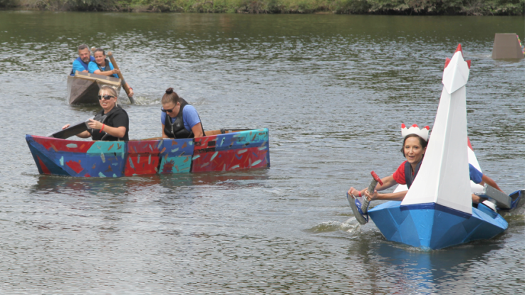 Three teams of two, each in a cardboard boat, paddle and race across Lake Macoupin.