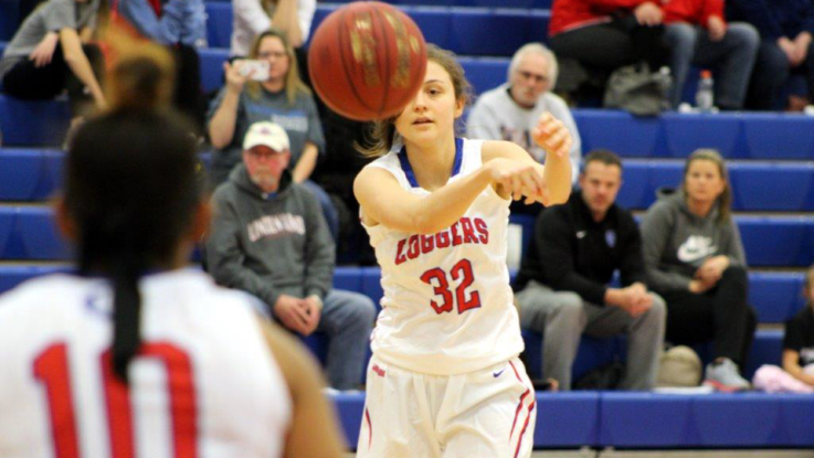 A women's basketball player passes the ball to a teammate. 