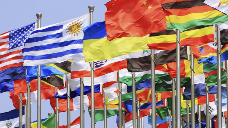 Multicolored flags from various countries blowing in the wind.