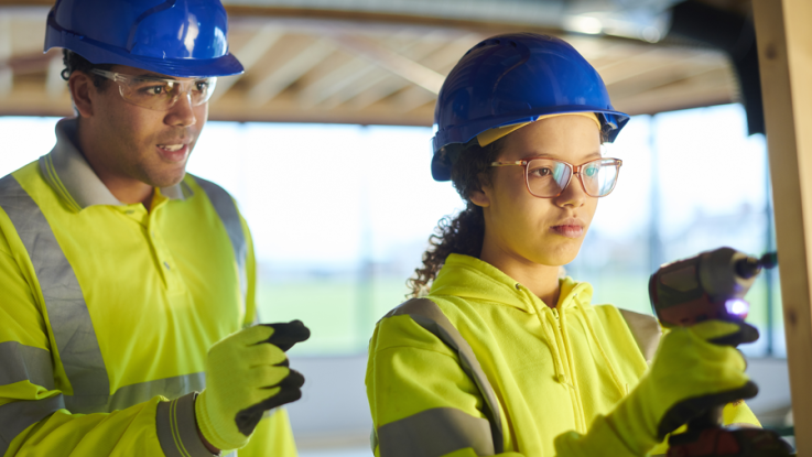 Photo of girl working with drill wearing a construction hat.