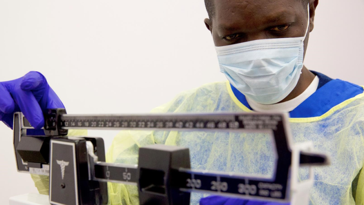 Man in scrubs operating a scale.