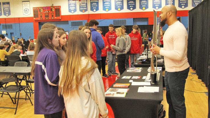 LLCC staff member talking to students in the exhibit area