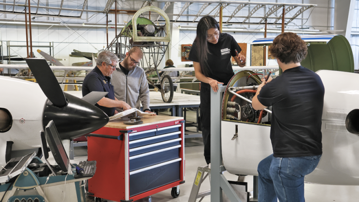 Aviation program director working with students on airplane engine in LLCC hangar