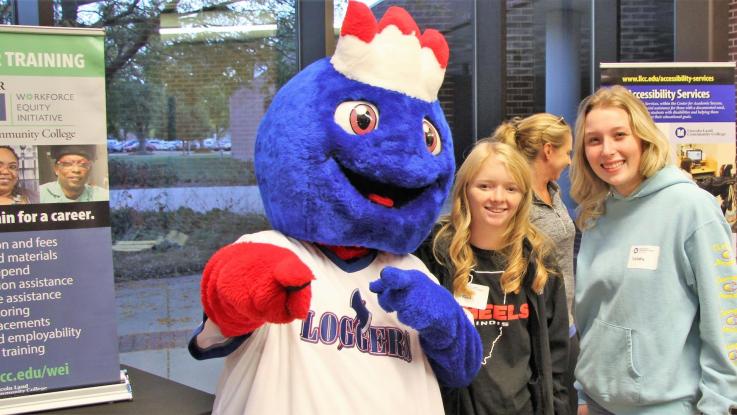 Linc standing with two prospective students in an exhibit area on campus
