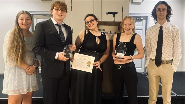 Phi Theta Kappa Honor Society student holding their chapter awards and smiling for a photo.