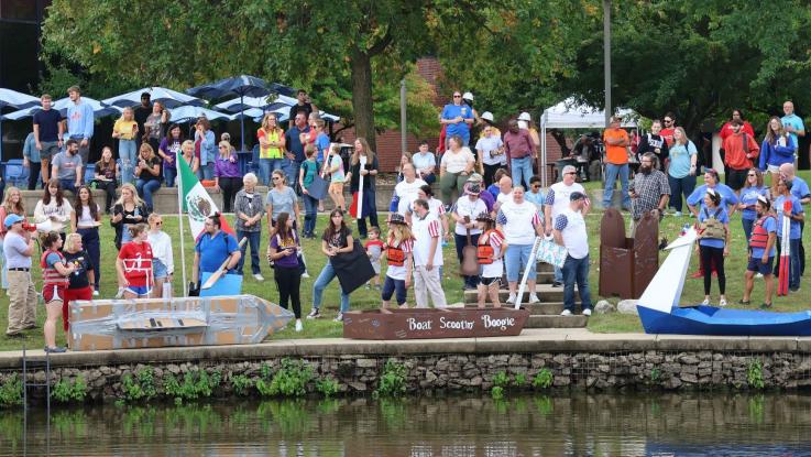 Boats getting ready to launch in regatta with members of the college community looking on.