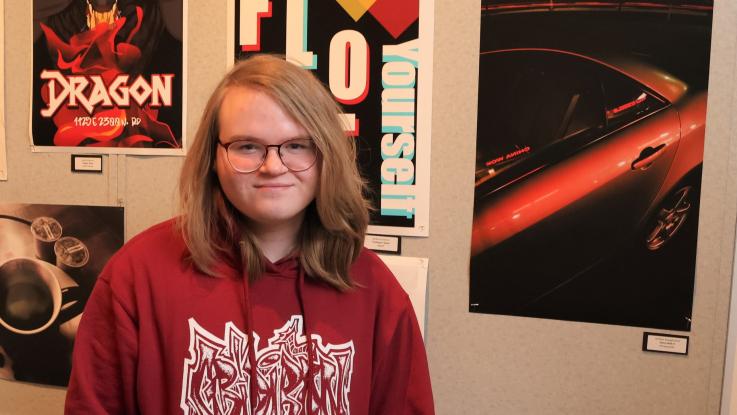 Student smiling for a photo next to artwork.