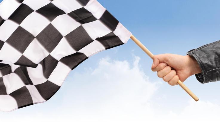 A hand waving a checkered race flag.