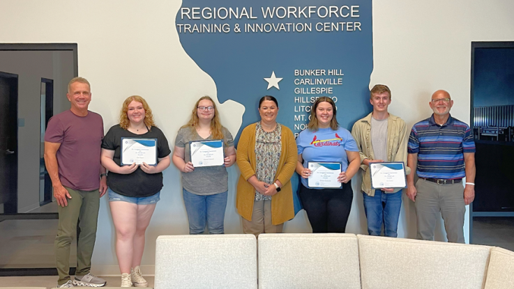 Four students stand with awards.