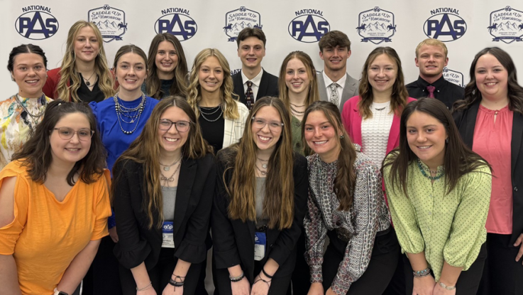 15 students pose for a photo at a convention.