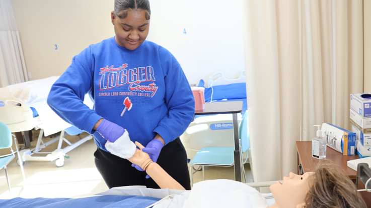 Student in LLCC shirt learning skills in nursing lab
