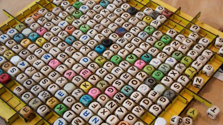Many boggle letter dice on table
