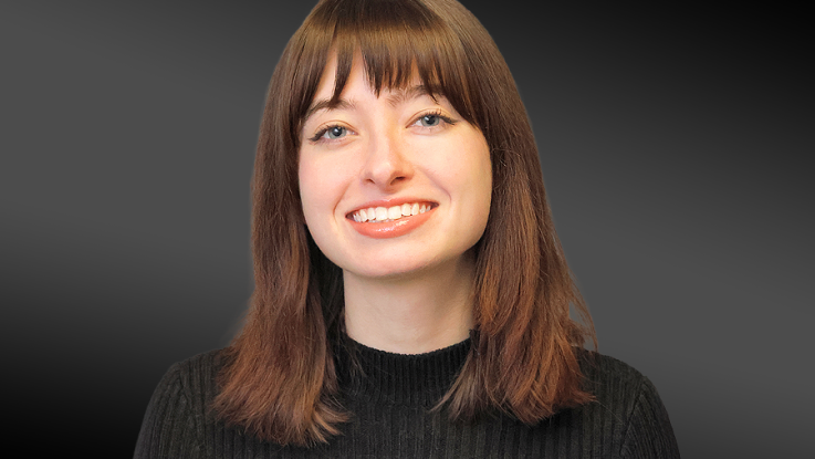 Studio portrait of Samantha Ulm with shoulder-length auburn hair, wearing a black sweater against a dark gray background.