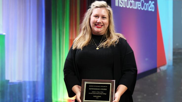 Woman holding an award near a colorful stage.