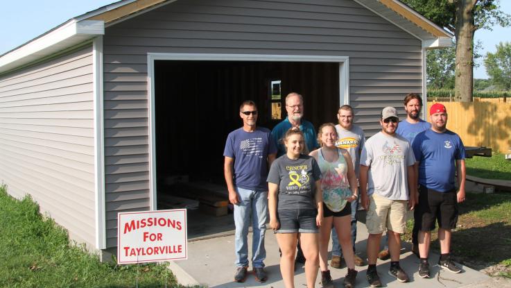 Students pose in front of the garage they built.