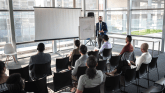 A man gives a presentation on a projection screen in front of a small audience