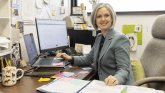 A college professor sits at her desk to prep coursework. 