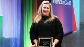 Woman holding an award near a colorful stage.