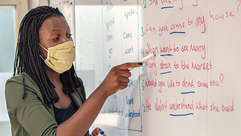 Person pointing to word on a dry erase board.