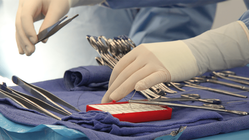 close-up of gloved hands with surgical instruments