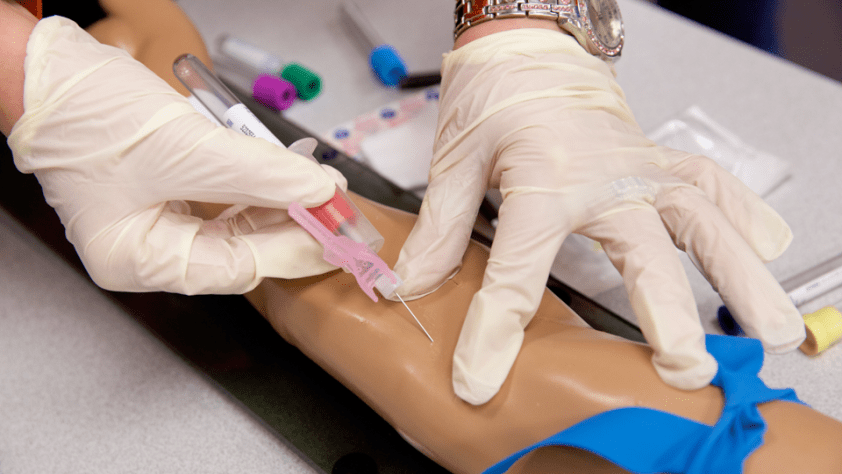 close-up of person drawing blood on a maniken