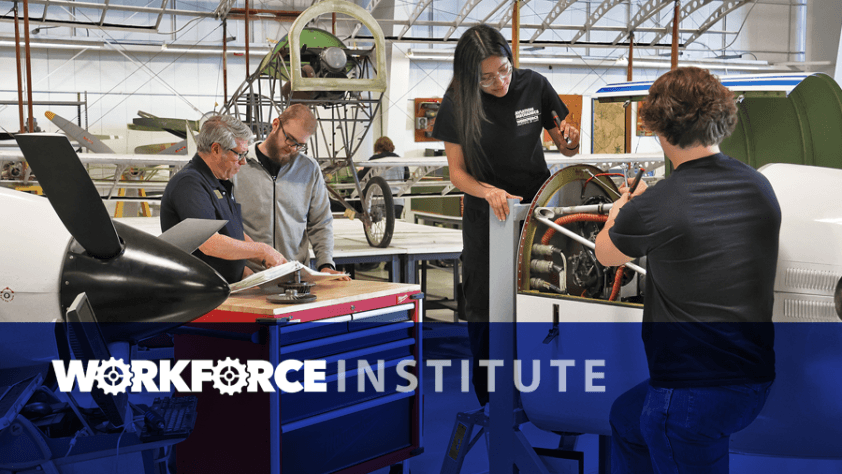 Students working with program director on engines in aviation hangar. Workforce Institute.