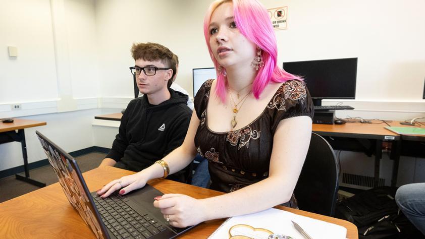 two engineering students in a classroom with their laptops