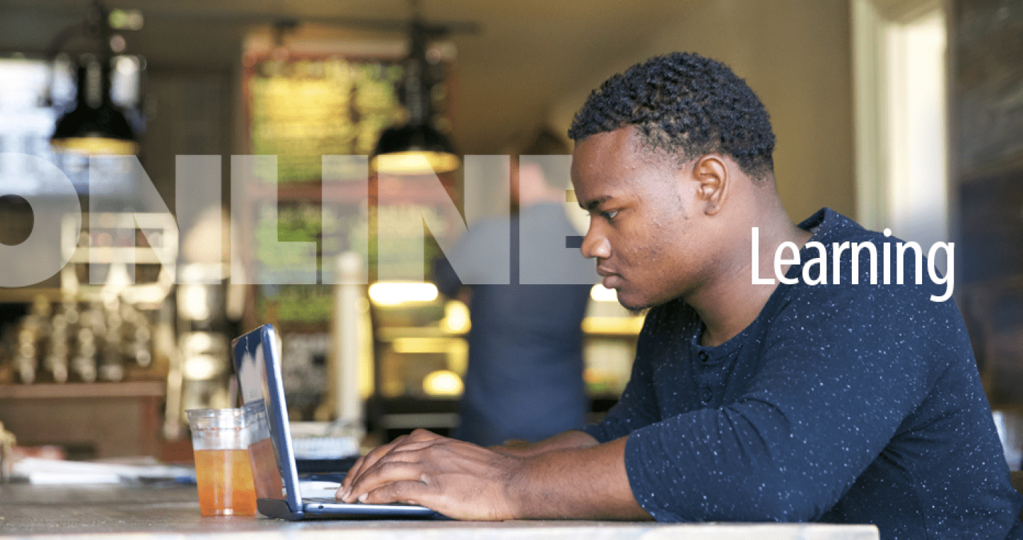 A student works on a laptop in a coffee shop.