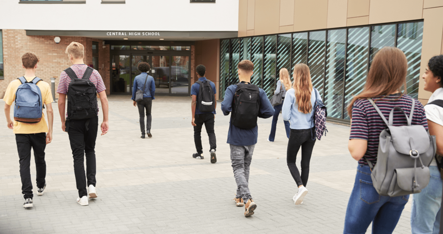 Students with backpacks walking into a high school.