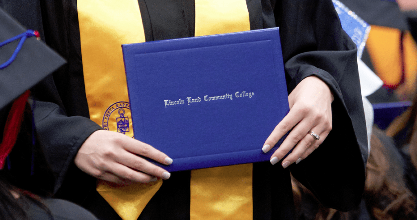 Graduate holding Lincoln Land Community College degree cover