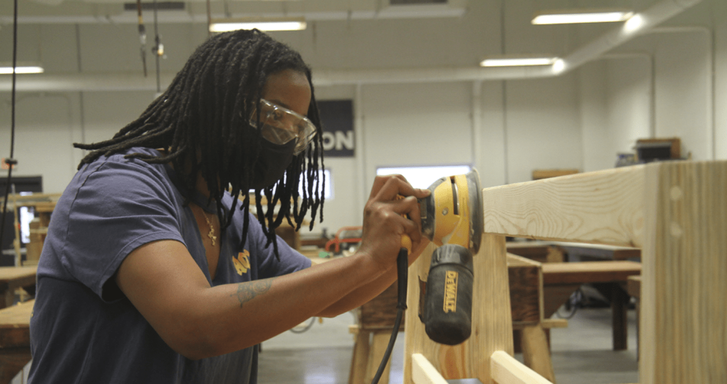 Student sanding wood in construction lab