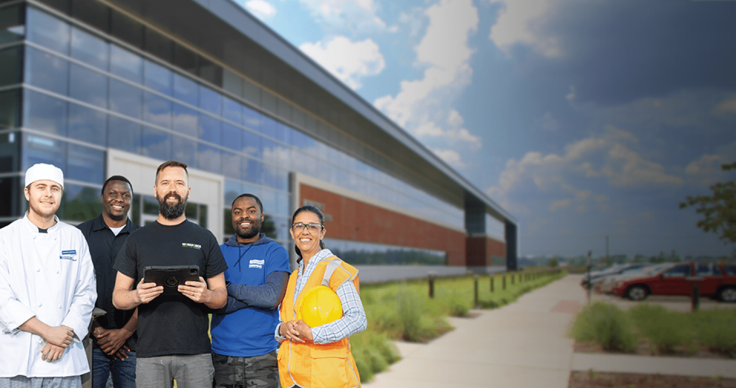 Four students from different career training programs standing around instructor holding tablet