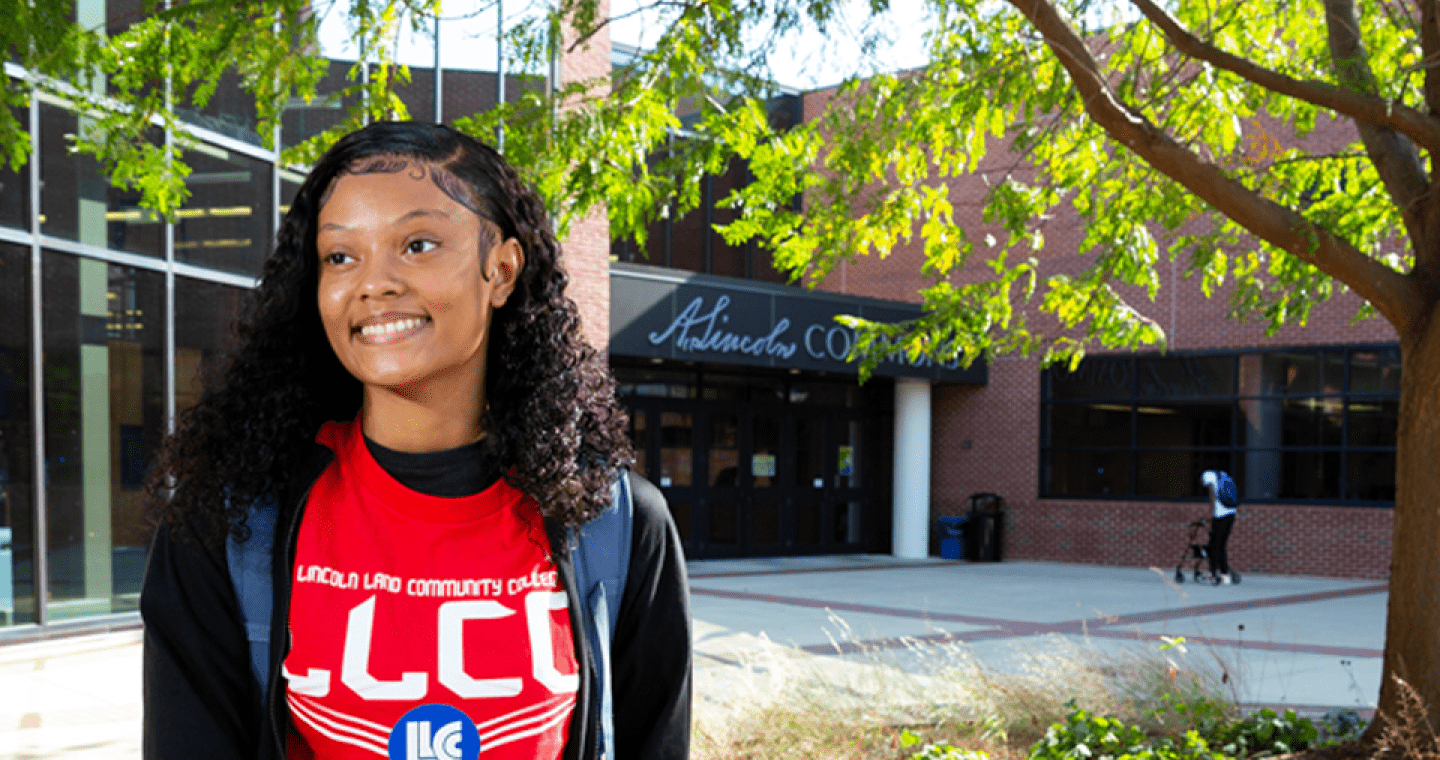Female student with LLCC shirt in foreground; A. Lincoln Commons in background